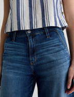 Person wearing AG JEANS blue jeans and a striped shirt on a plain background