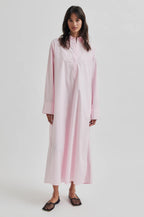 Woman wearing a long pink dress on a white background
