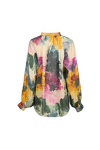 A long-sleeve blouse with a vibrant watercolor floral print on a light cream base, featuring yellow, pink, purple, and green tones, shown against a solid light gray background.

de29ar.4056
Hannes Roether