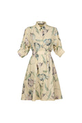 A light beige shirt dress with a green and gray floral print, featuring a collar, button-up front, and a matching fabric tie belt at the waist, shown against a solid light blue-gray background.
be28st-k.4057
hannes Roether