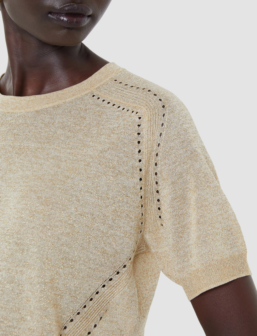 Beige knit top with intricate detailing on a neutral background