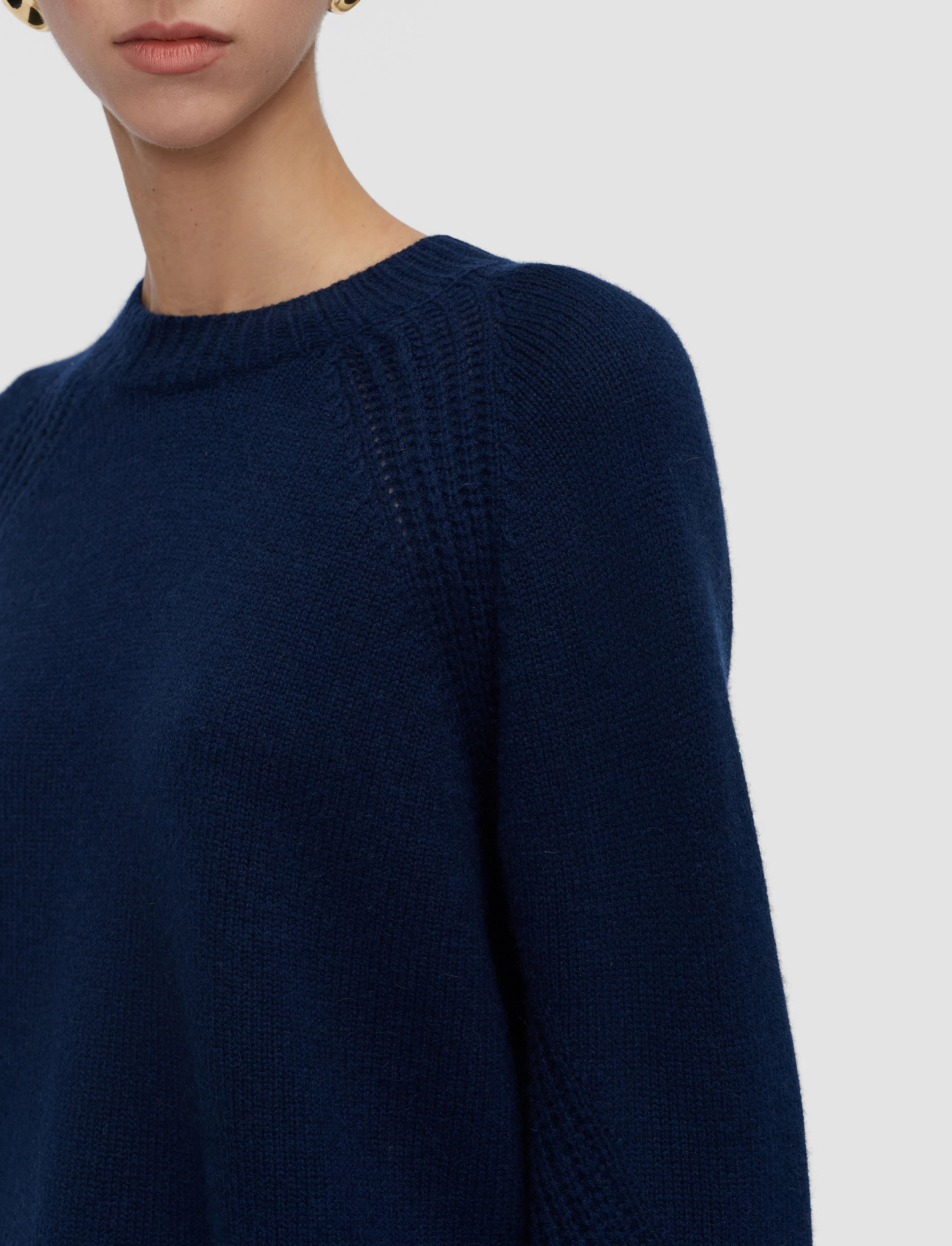 Navy blue sweater worn by a person on a light gray background