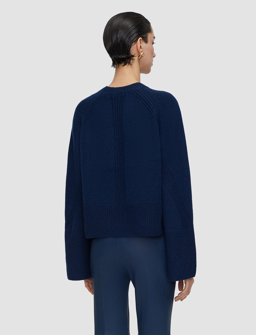 Person wearing a navy blue sweater and pants on a light gray background