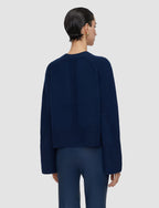 Person wearing a navy blue sweater and pants on a light gray background