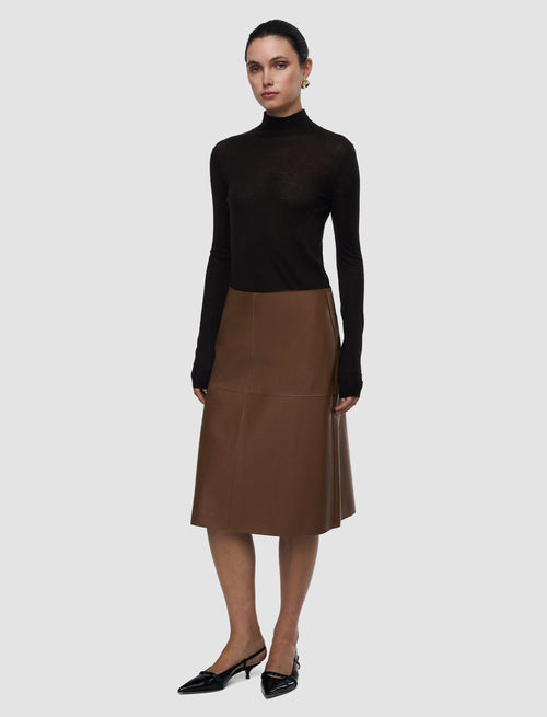 Woman wearing a black turtleneck and brown leather skirt on a white background