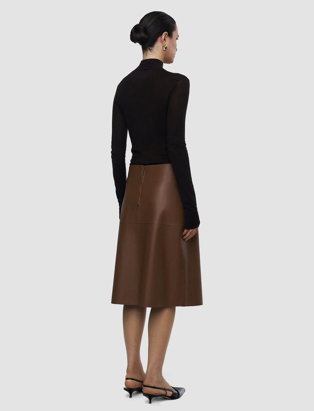 Woman wearing a black top and brown leather skirt on a white background
