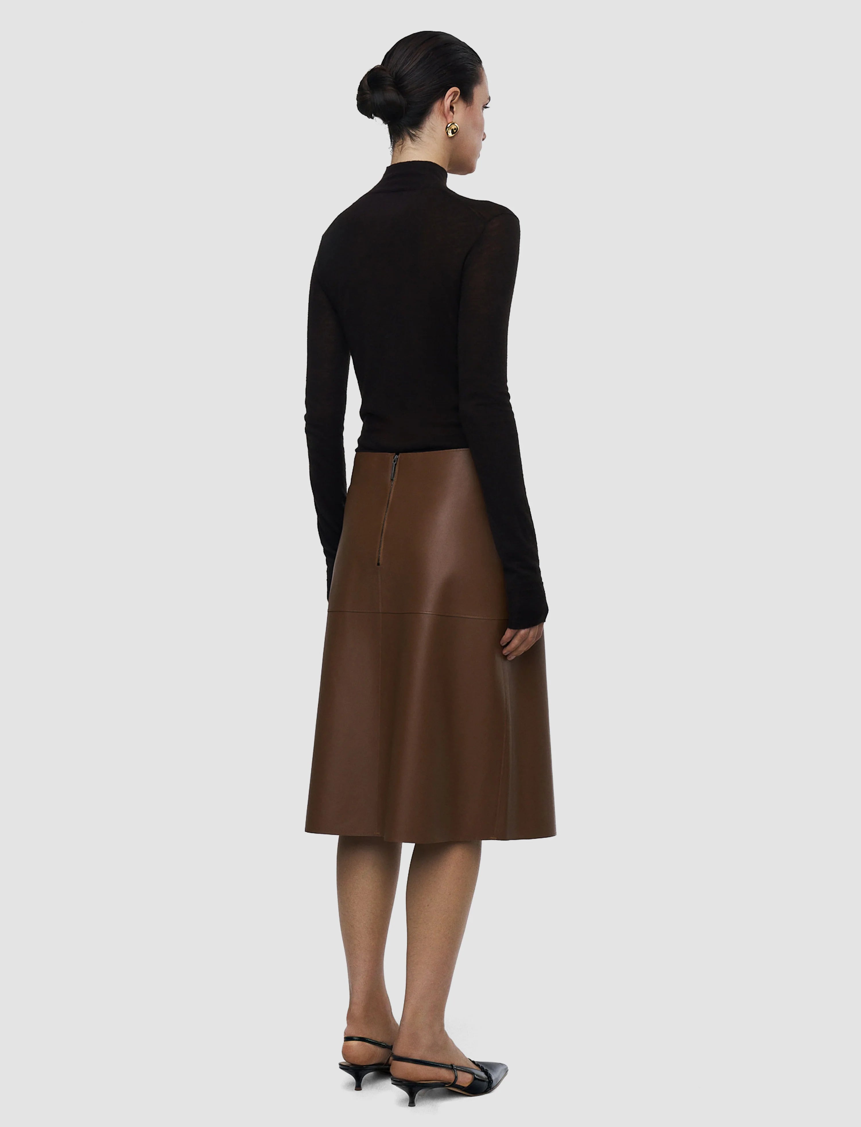 Woman wearing a black top and brown leather skirt on a white background