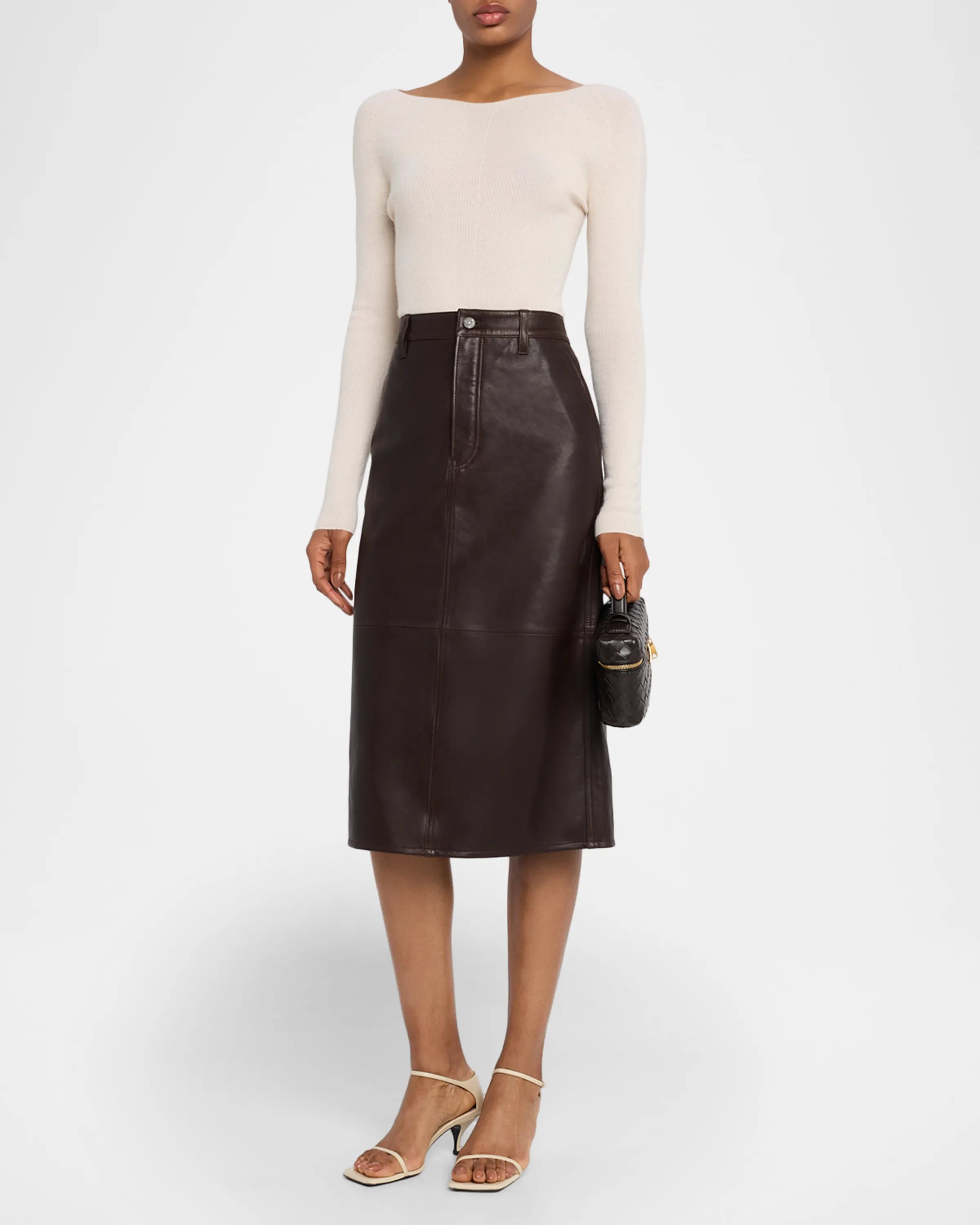 Person wearing a brown leather skirt with a white top on a white background