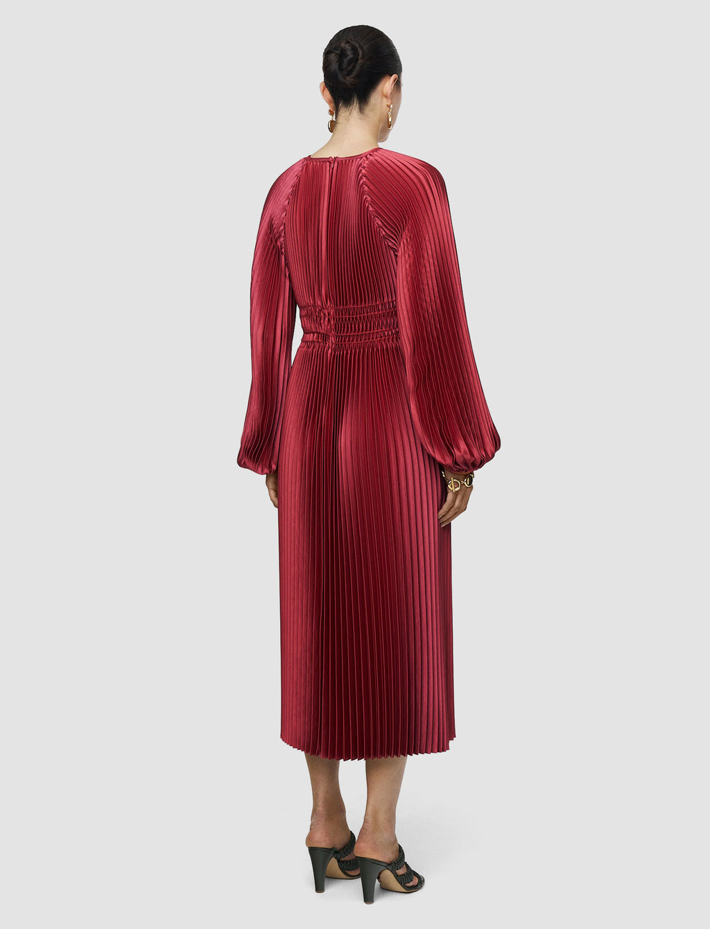 Red pleated dress worn by a person on a white background