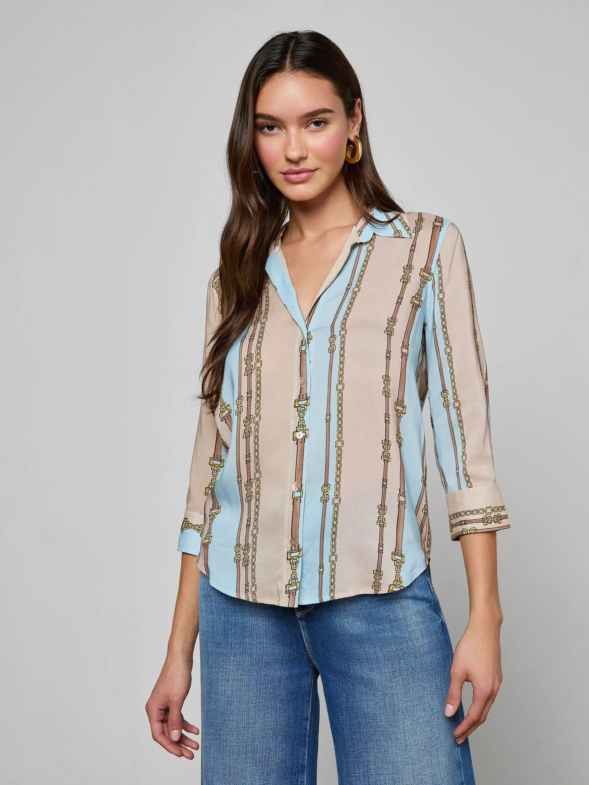 Woman wearing a patterned blouse with long sleeves on a gray background