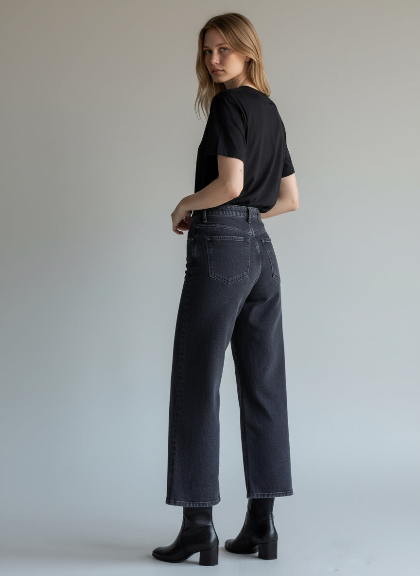 Woman wearing black jeans and a black shirt against a plain background