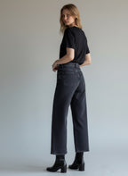Woman wearing black jeans and a black shirt against a plain background