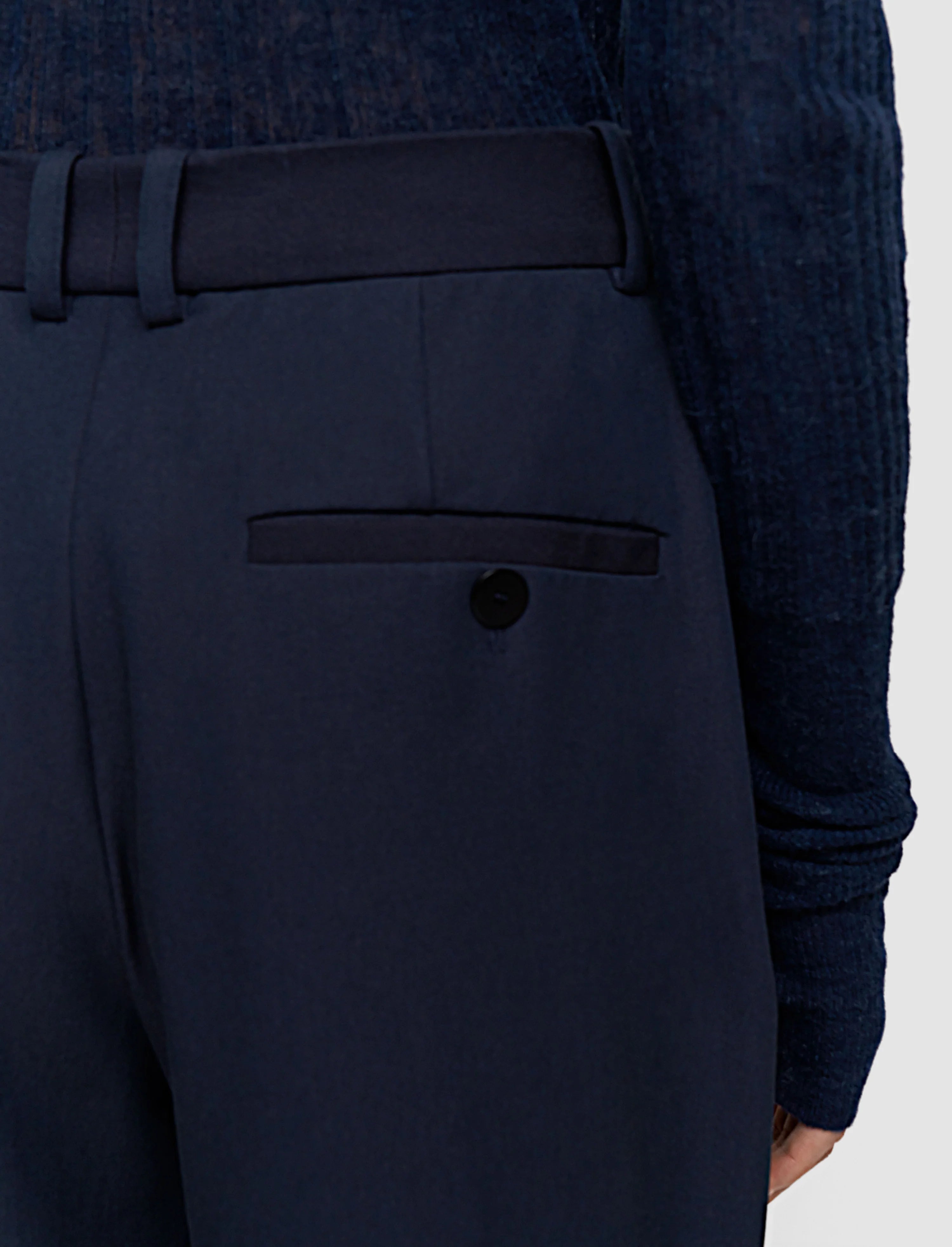 Navy blue suit pants with a button on a light gray background