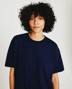 A person wearing a deep navy, short-sleeved crew neck t-shirt.